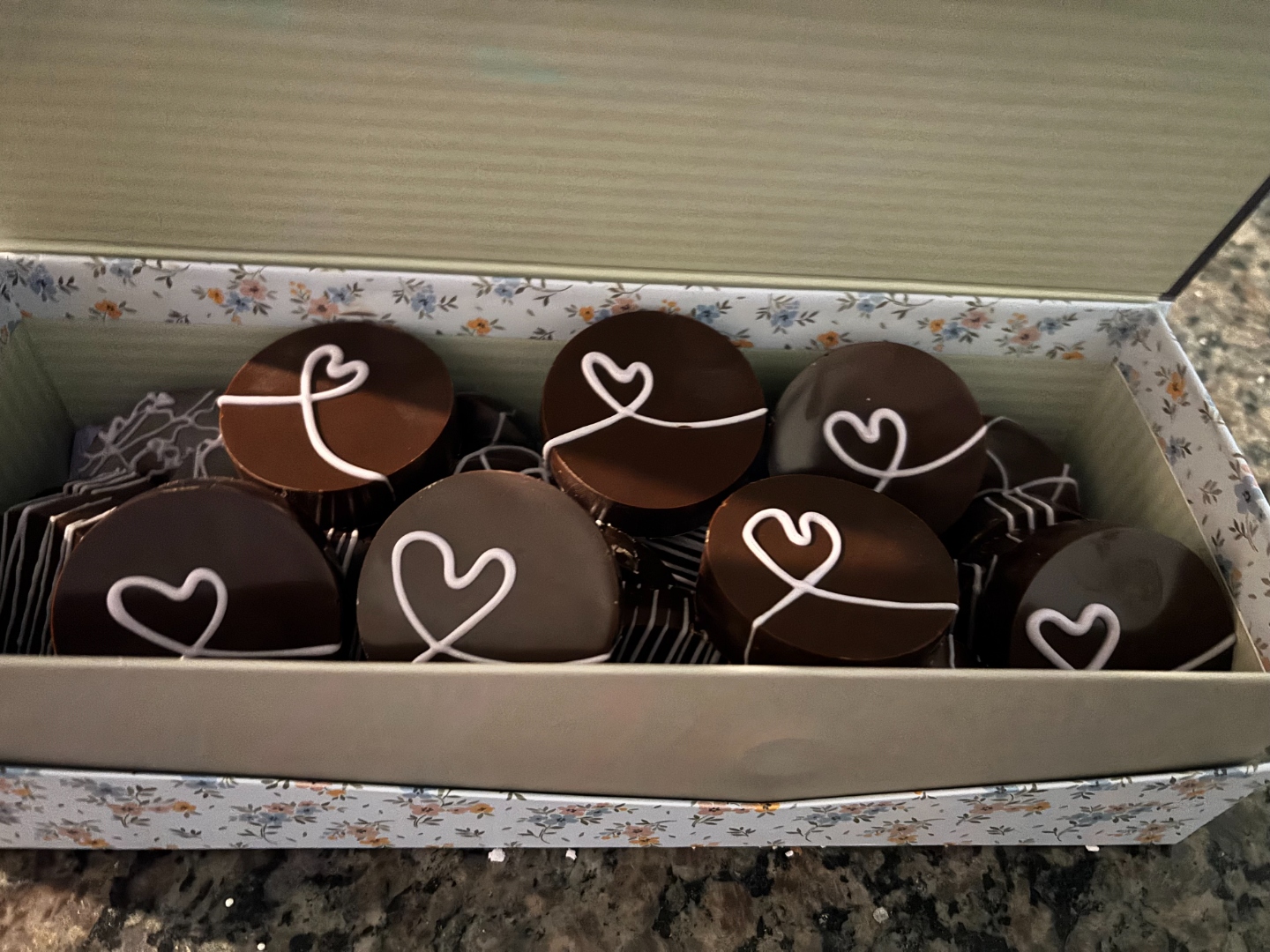 A gift box filled with heart-decorated chocolate covered Oreos